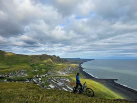 Ein Radfahrer blickt während einer 1-stündigen E-Mountainbike-Tour auf Vik und seine atemberaubende Küstenlinie.