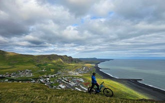 Ein Radfahrer blickt während einer 1-stündigen E-Mountainbike-Tour auf Vik und seine atemberaubende Küstenlinie.