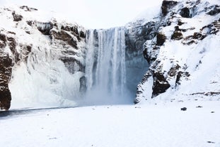 Capture the surreal beauty of Skogafoss in winter's grip, as the waterfall's powerful flow is partially frozen.