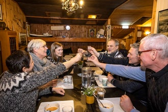 Three people sitting around a table raise their glasses for a toast inside a Reykjavik restaurant.