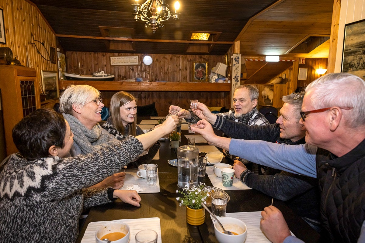Three people sitting around a table raise their glasses for a toast inside a Reykjavik restaurant.