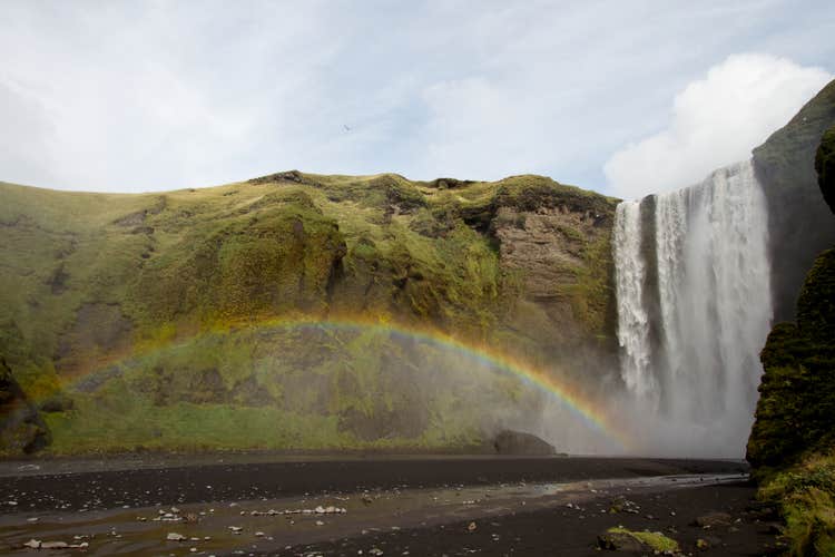A rainbow appears, adding to the majestic beauty of the Skogafoss waterfall.