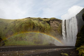 A rainbow appears, adding to the majestic beauty of the Skogafoss waterfall.