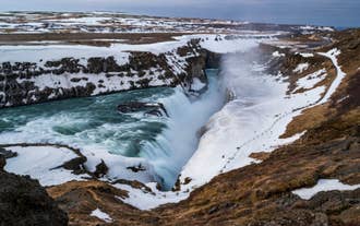 Gullfoss-waterval in de winter, met een met sneeuw bedekte kloof en krachtig neerstortend water.