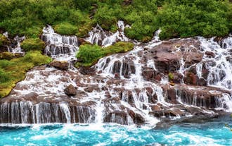 Cascadas de Hraunfossar fluyendo a través de un campo de lava en el oeste de Islandia.