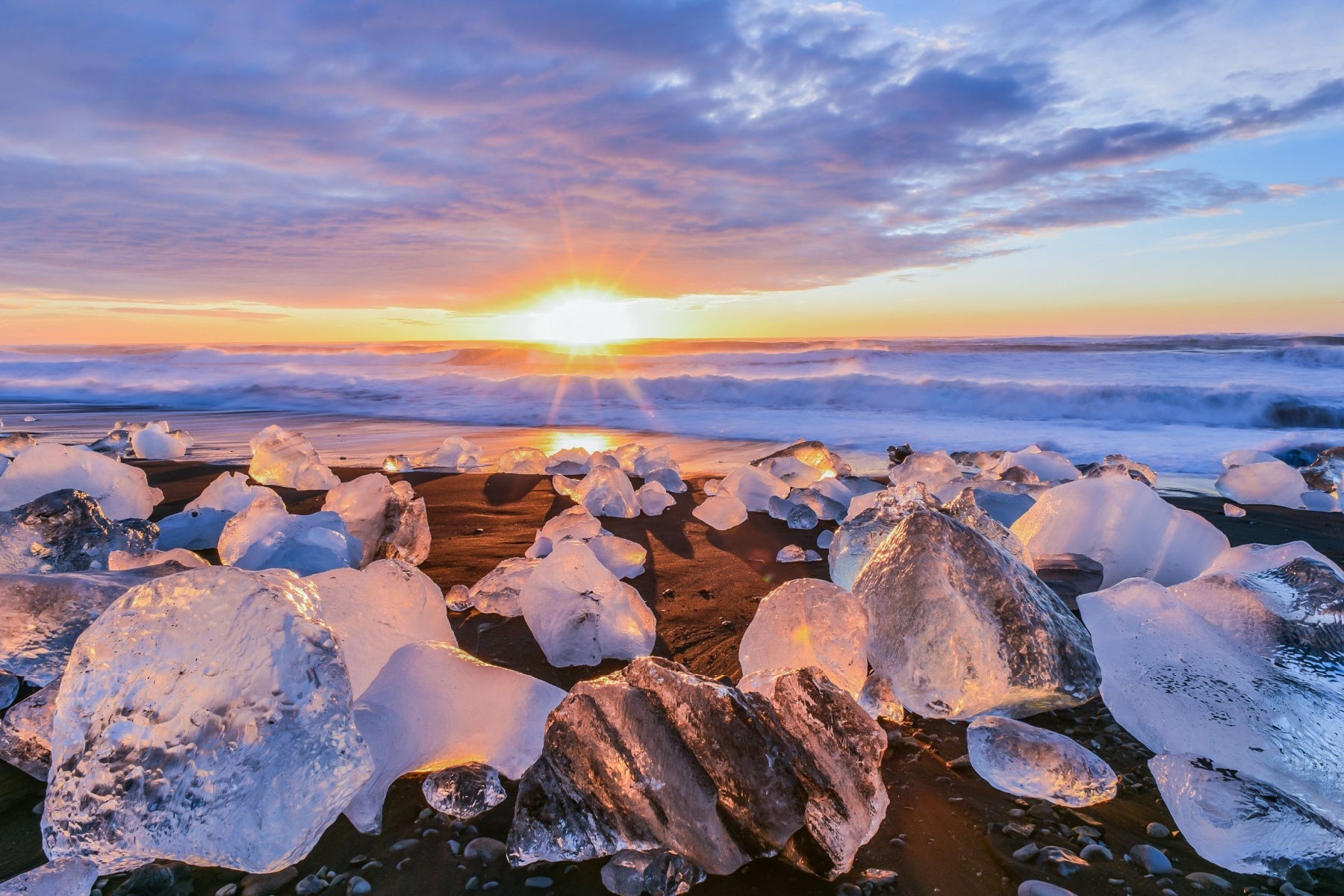 Diamond Beach with ice chunks on black sand at sunrise in South Iceland.