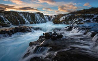 De Bruarfoss-waterval van de Golden Circle met felblauw water dat over donkere vulkanische rotsen stroomt.