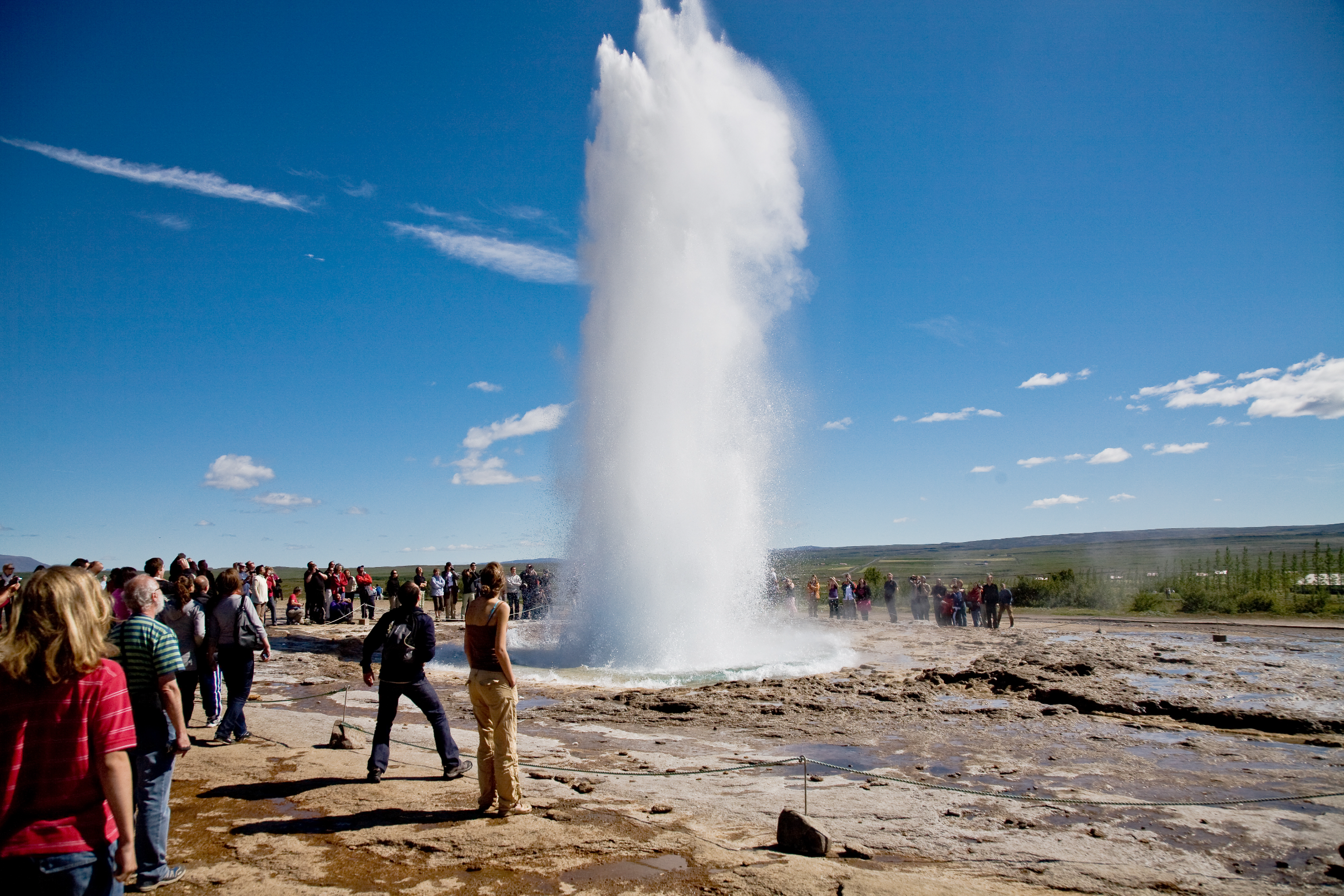 El géiser Strokkur haciendo erupción y lanzando agua a gran altura en la zona geotérmica de Geysir.