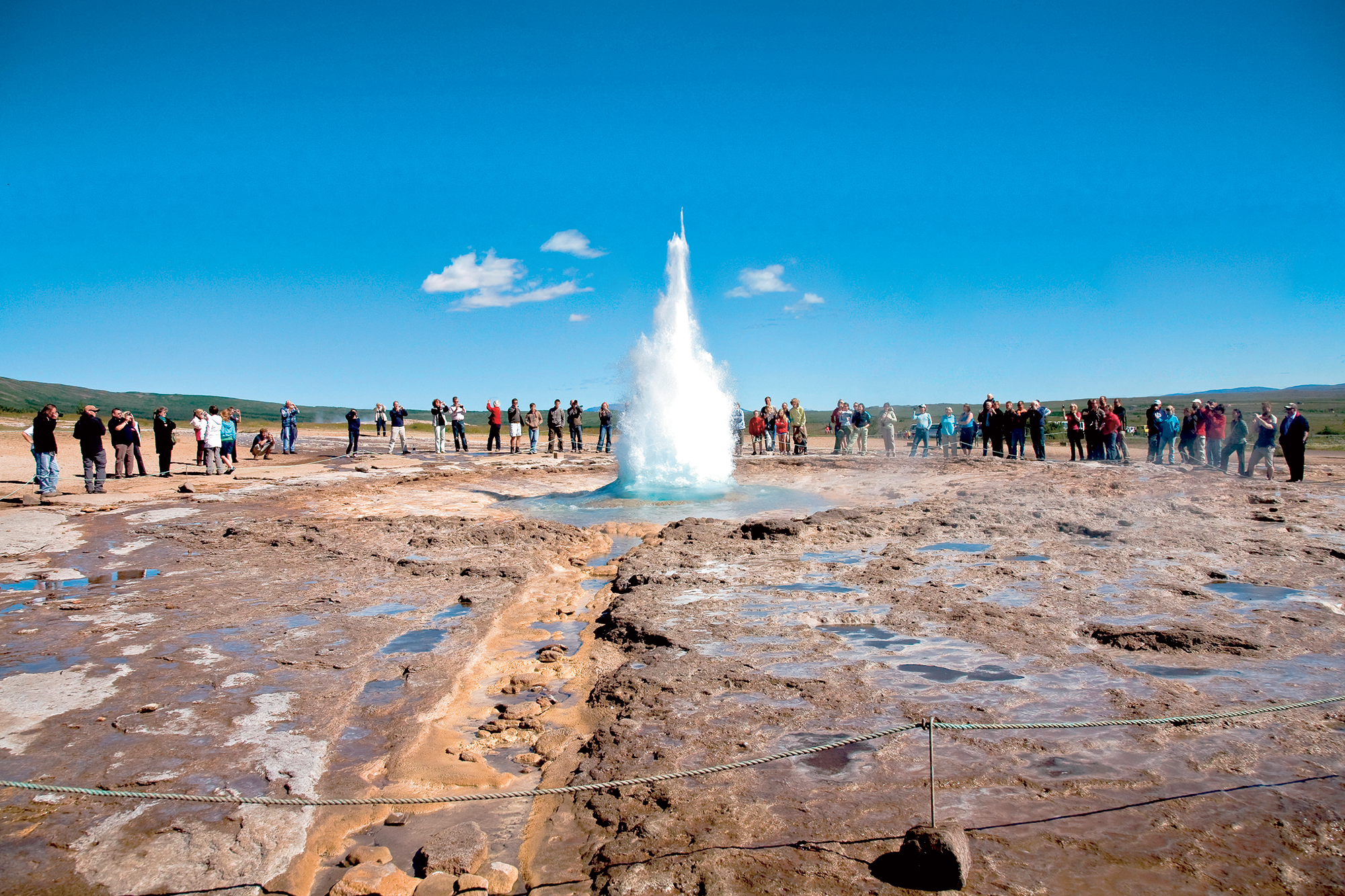 ผู้คนต่างเฝ้าดูขณะที่ไกเซอร์ Strokkur ปะทุสูงขึ้นไปในอากาศในเขตความร้อนใต้พิภพ Geysir ในหุบเขา Haukadalur