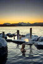 Folk slapper af i Hvammsvik Hot Springs i skumringen i Island.