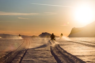 Schneemobilfahrer ziehen bei Sonnenuntergang frische Spuren über den Langjökull-Gletscher.