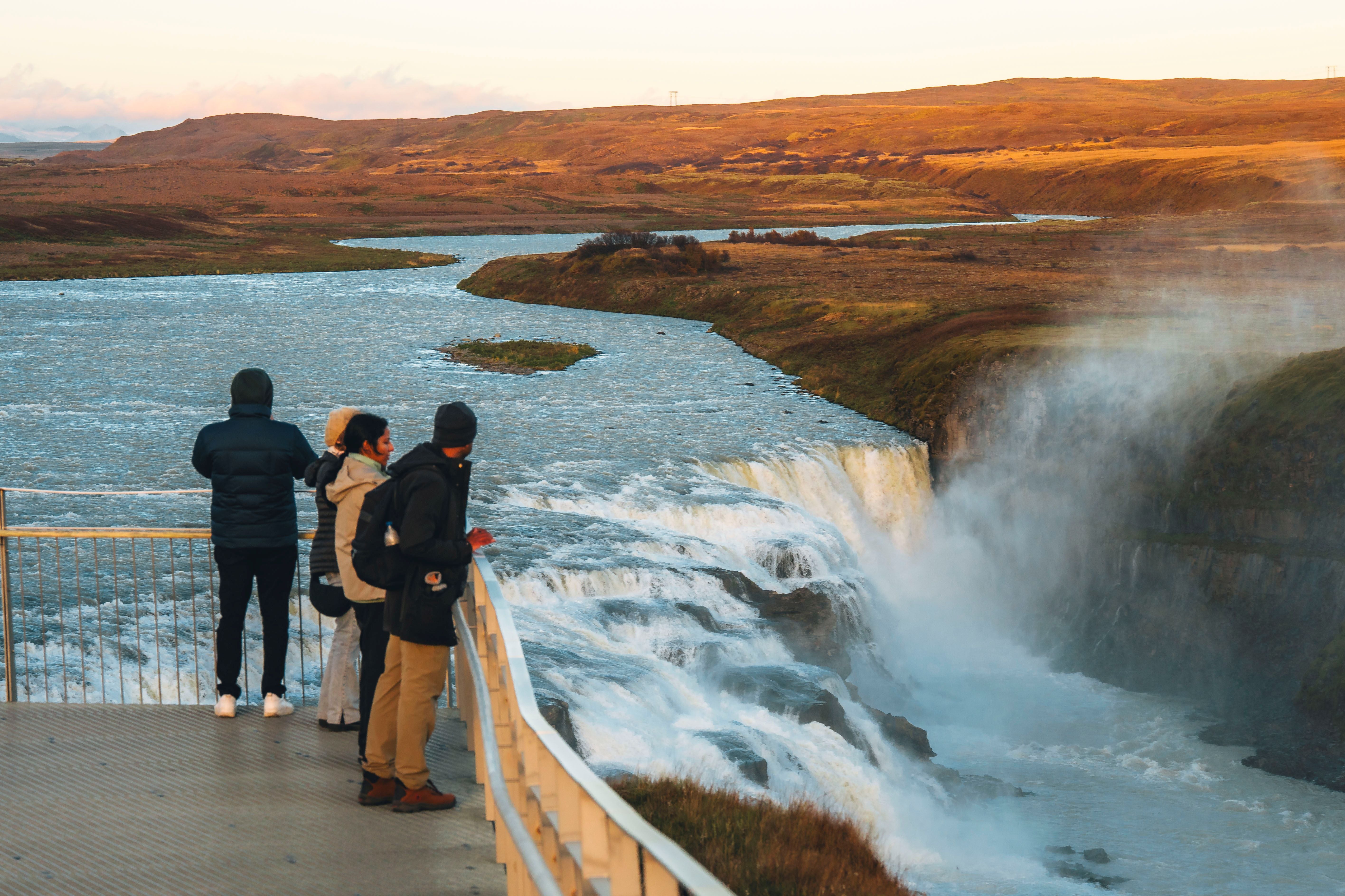 Travelers watch Gullfoss Waterfall from a viewing platform on a small-group Golden Circle tour.