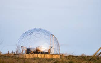 A glamping pod at Aurora Igloo, with a small table and two chairs facing outward.