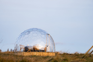 En glampingpod på Aurora Igloo, med et lite bord og to stoler som vender utover.