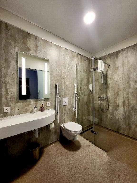 Experience chic comfort in the modern bathroom of Hotel Flokalundur, featuring stylish accents and thoughtful amenities.