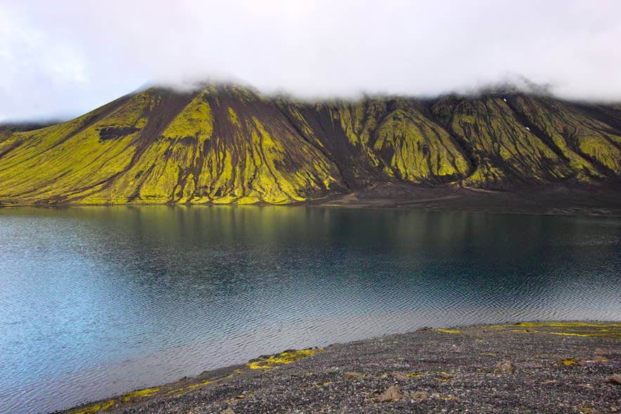 Lac Langisjor en Islande, avec une eau calme et des montagnes couvertes de mousse sous des nuages bas dans les Hautes Terres