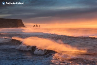 Le onde si infrangono sulla spiaggia di Reynisfjara al tramonto.