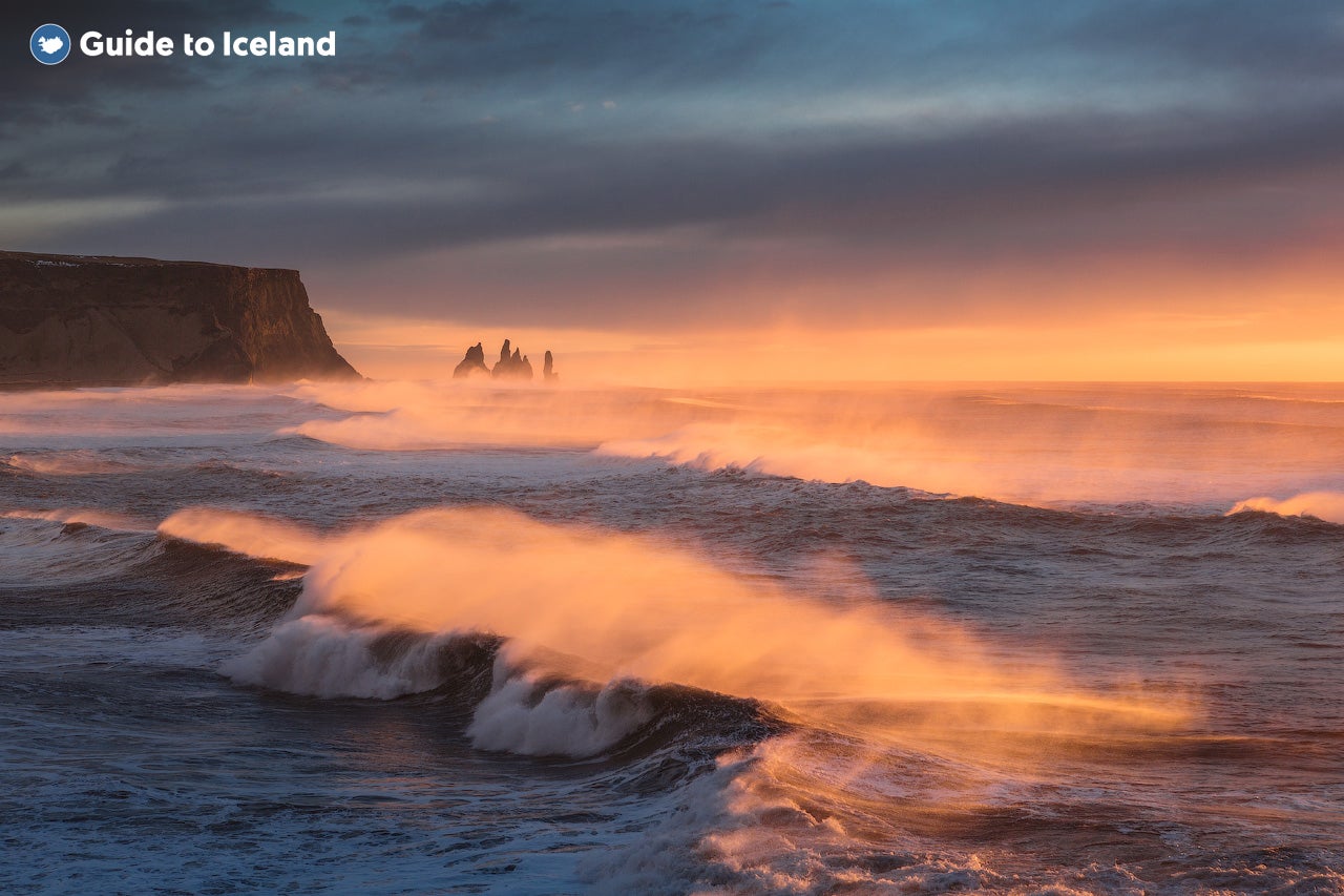 Waves roll into Reynisfjara beach at sunset.