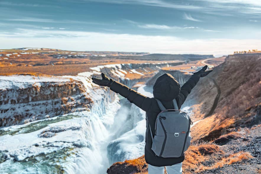 Traveler admiring Gullfoss Waterfall in spring along the Golden Circle route in Iceland.