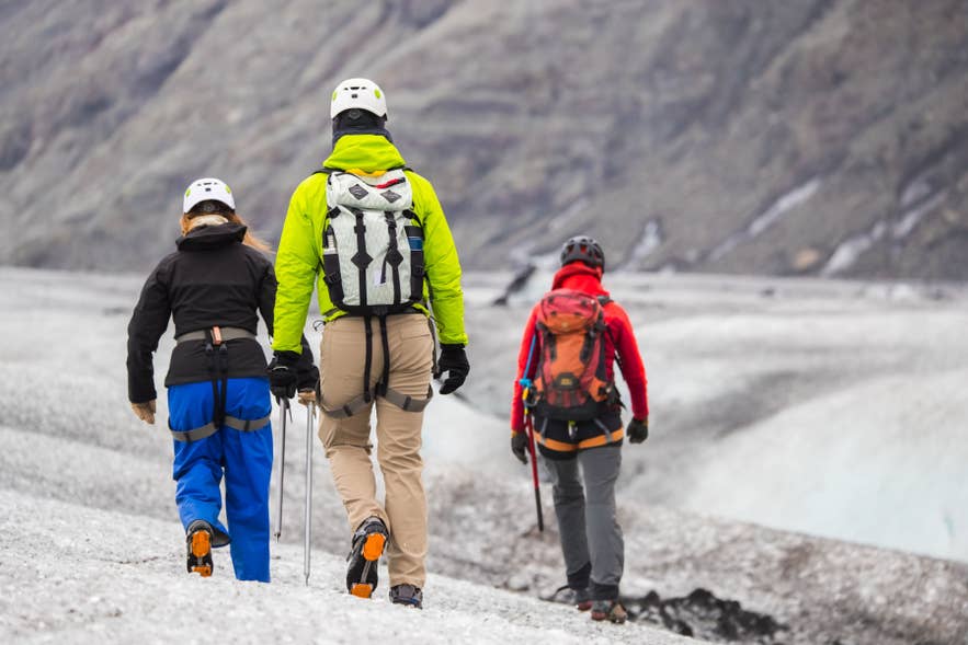 Group hiking on glacier with helmets and gear in Iceland.