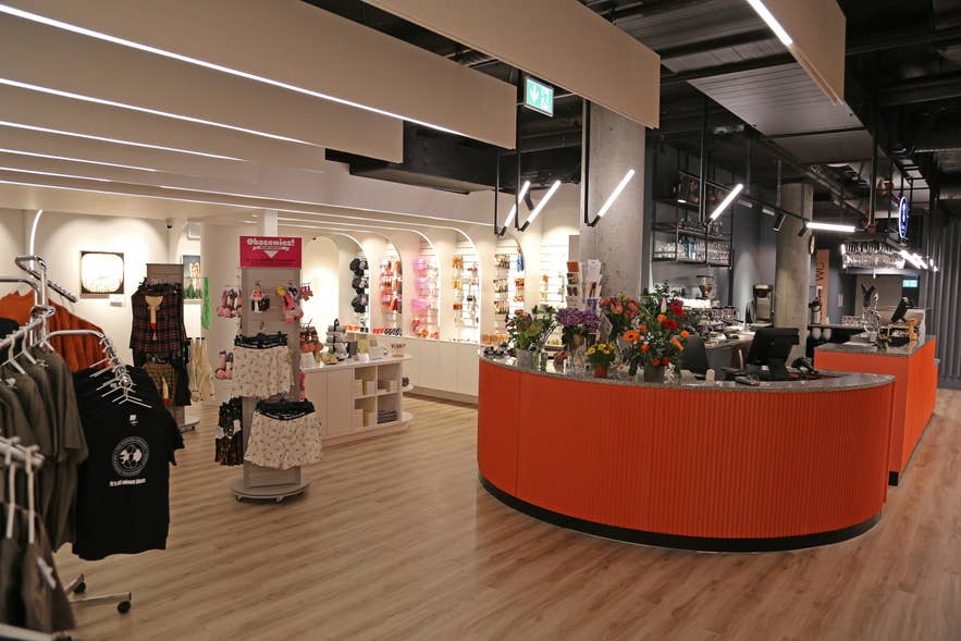 Gift shop at the Icelandic Phallological Museum with displays of t-shirts, themed merchandise, and a curved orange service counter. Gift shop at the Icelandic Phallological Museum with displays of t-shirts, themed merchandise, and a curved orange service counter.
