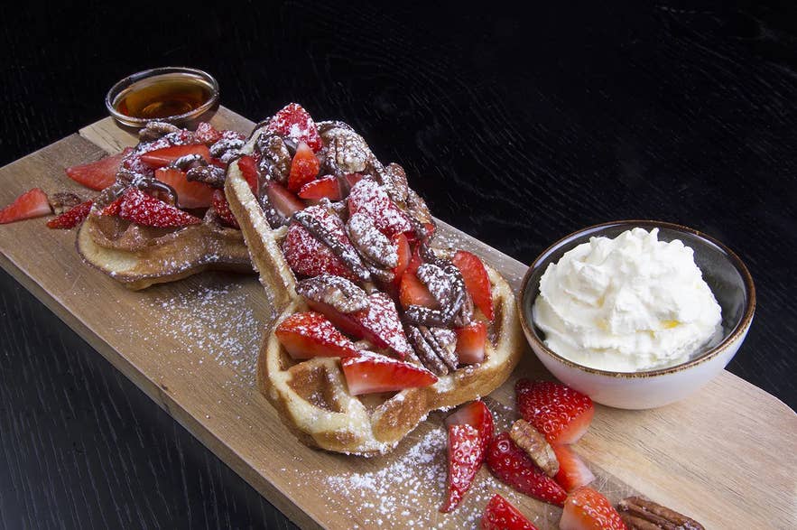 A phallus-shaped waffle at The Phallic Cafe inside the Icelandic Phallological Museum, topped with strawberries, chocolate sauce, powdered sugar, and served with whipped cream and maple syrup. A phallus-shaped waffle at The Phallic Cafe inside the Icelandic Phallological Museum, topped with strawberries, chocolate sauce, powdered sugar, and served with whipped cream and maple syrup.