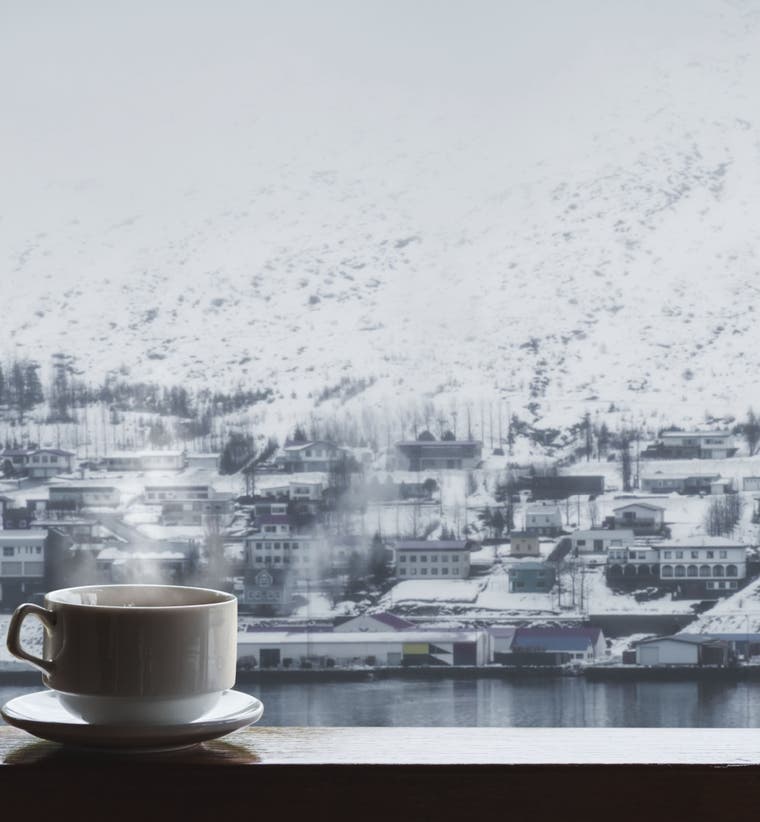 Warm coffee by a window overlooking a snowy Iceland town in winter.