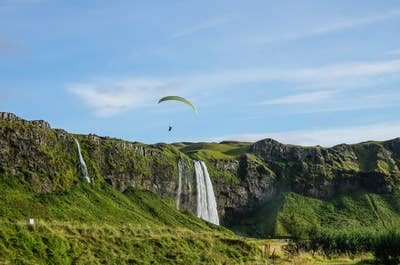 Paralotniarz szybuje nad wodospadem Seljalandsfoss w południowej Islandii.