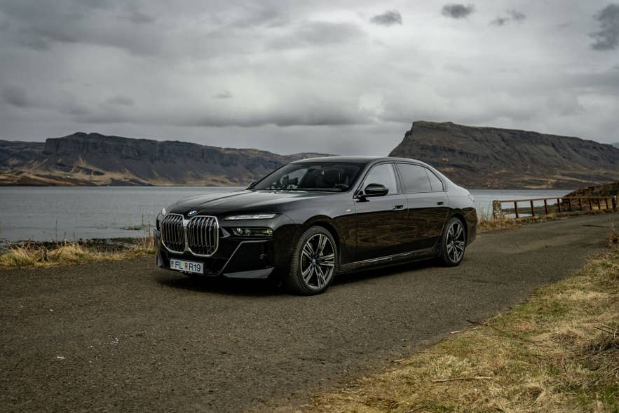 Luxury car parked by scenic Icelandic coastal landscape under cloudy sky