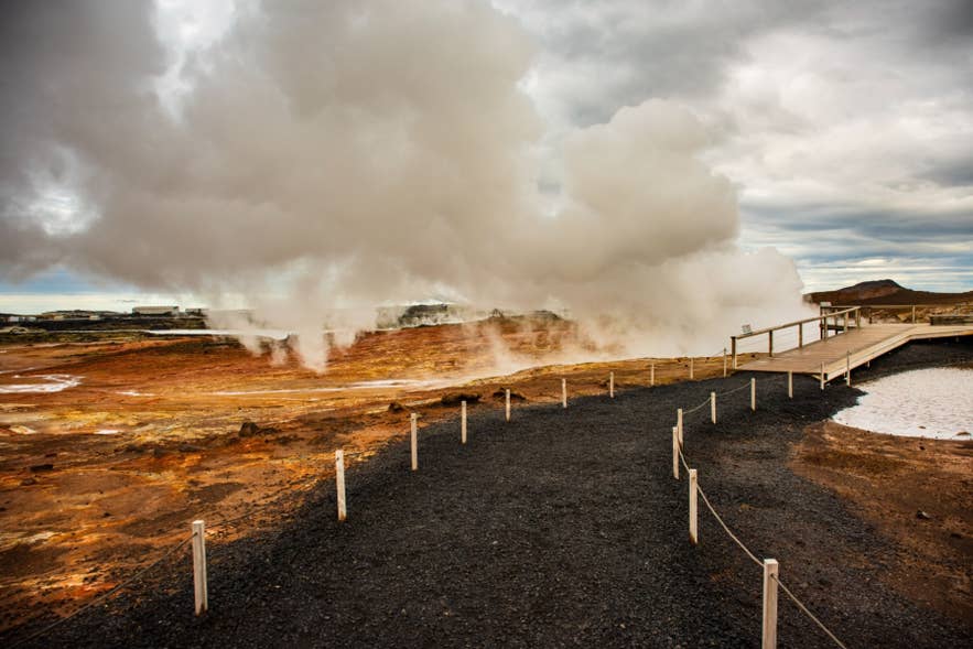 Walking path through Hverir geothermal area in Namafjall, Iceland, with steaming fumaroles and colorful mineral-rich ground.