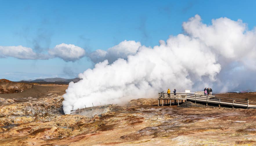 Visitors stand on a wooden boardwalk near powerful steam vents at Gunnuhver geothermal area on the Reykjanes Peninsula, Iceland.