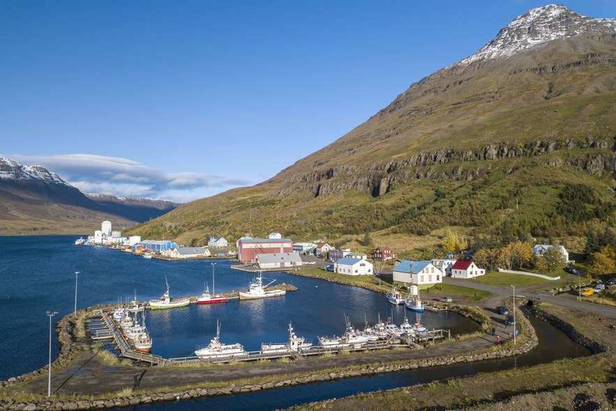 Aerial view of the colorful Seydisfjordur village nestled between steep mountains and the sea in Iceland's fjords.