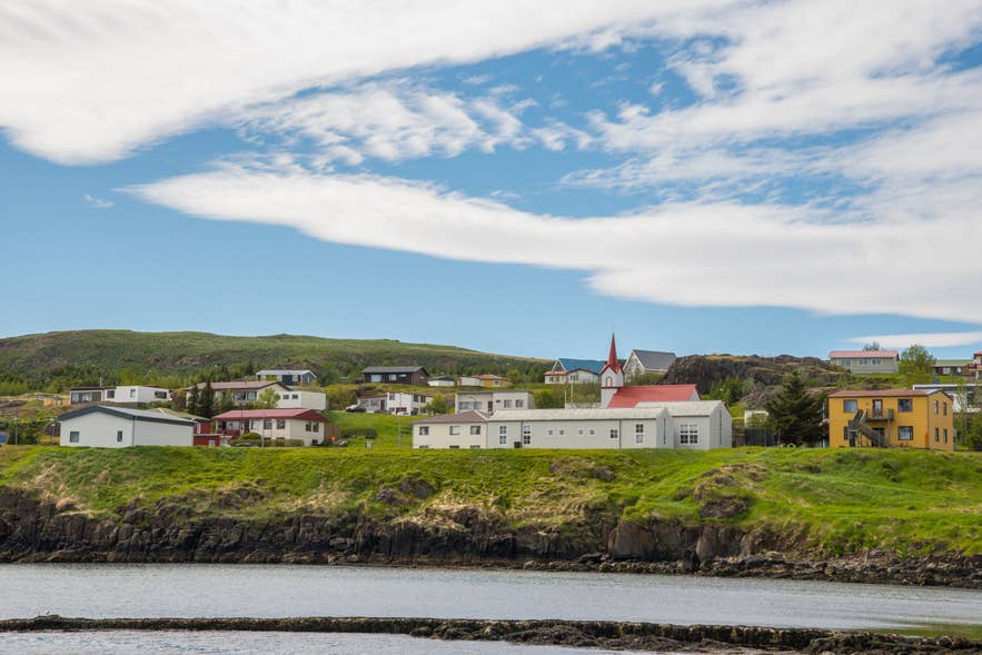 A view of the coastal village of Vopnarfjordur, showcasing a scenic fjord in Iceland with colorful houses and greenery.