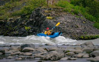 Solo paddler on an inflatable kayak navigates rocky rapids on the Hvita River.
