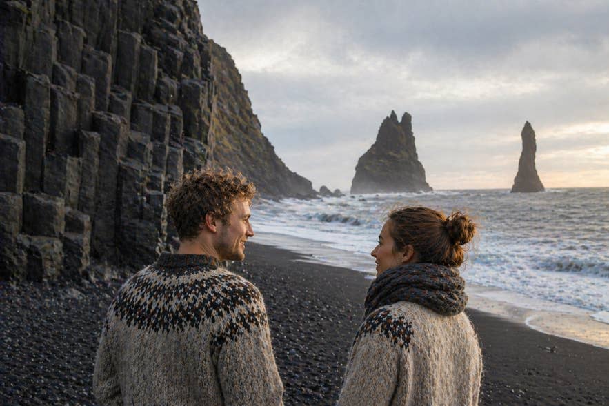 Two people discussing Icelandic names at Reynisfjara Black Sand Beach.