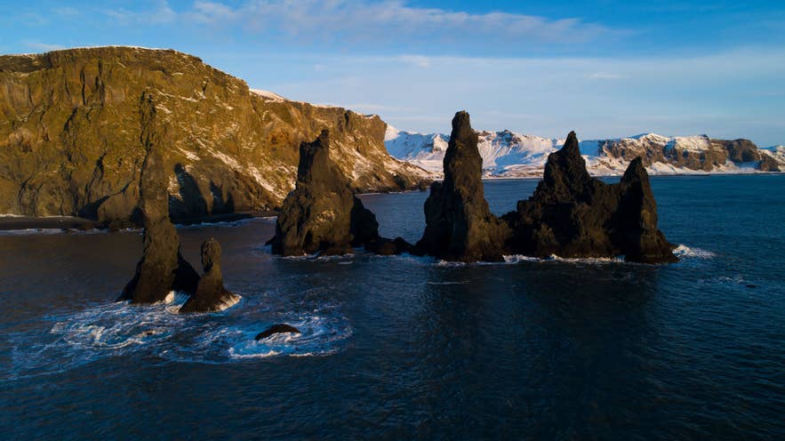Reynisdrangar sea stacks rising from the ocean beside Reynisfjara black sand beach in South Iceland Reynisdrangar sea stacks rising from the ocean beside Reynisfjara black sand beach in South Iceland