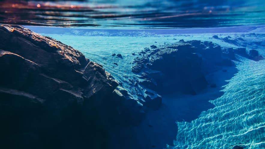 Silfra fissure in Thingvellir National Park shows the gap between tectonic plates beneath clear blue water in Iceland.