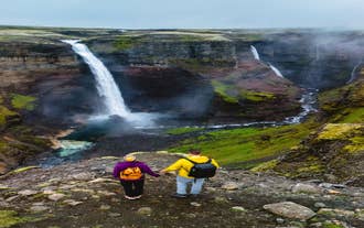 Travelers hiking near a waterfall in the Highlands of Iceland.