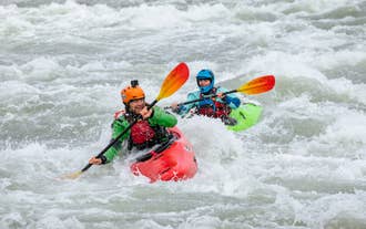 Two kayakers navigate fast whitewater rapids on the Hvita river during a South Iceland inflatable kayak tour.