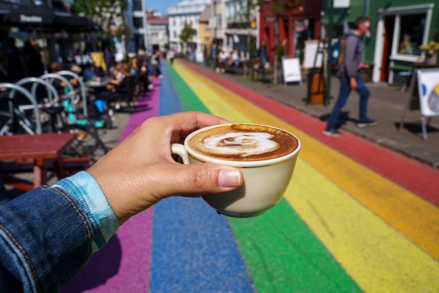 Hand holding a cup of cappuccino on Rainbow Street in downtown Reykjavik.