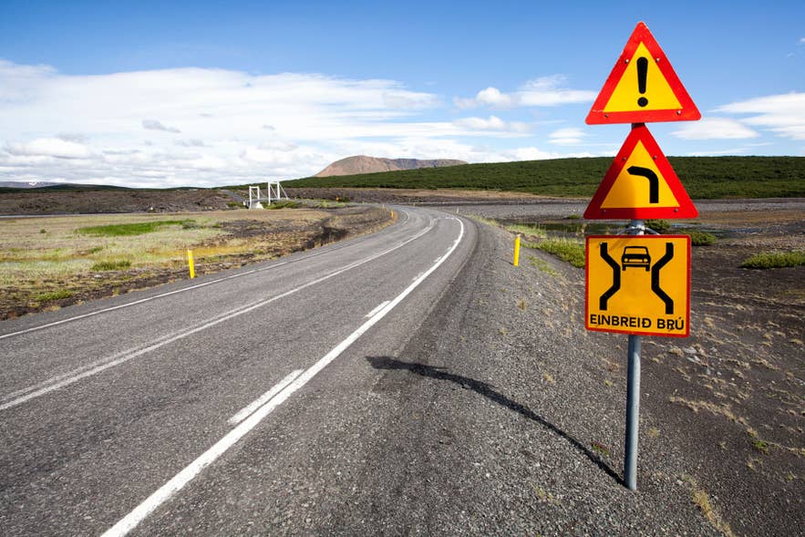 Icelandic road with warning signs and scenic highland landscapes along a remote route in East Iceland