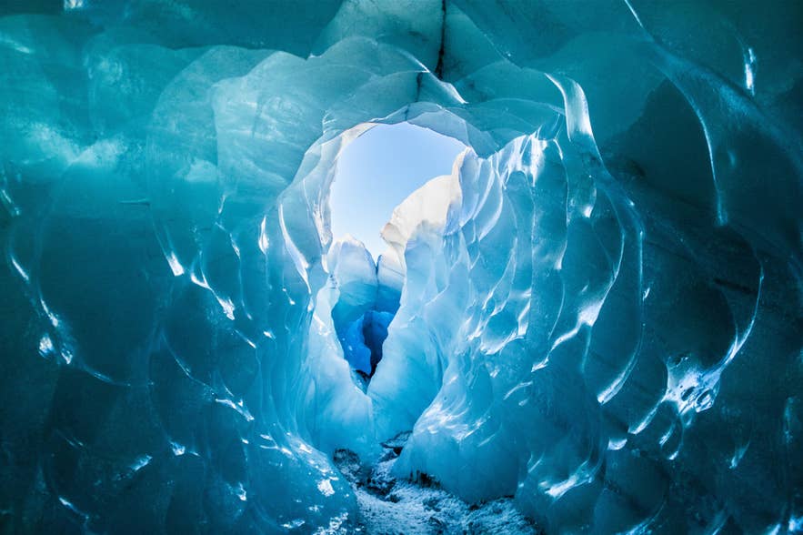 Close-up view of glowing blue ice formations inside a natural glacier cave in Iceland.