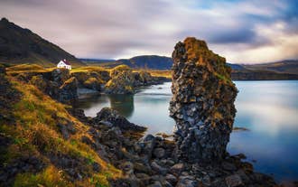 Arnarstapi showcasing its rugged coastal cliffs beneath the eclipse-darkened sky.
