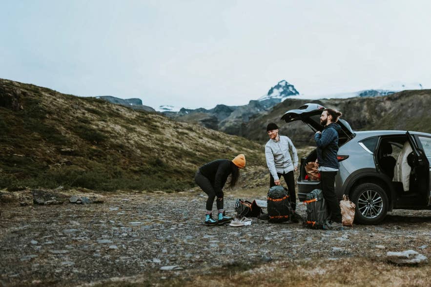 Travelers loading luggage onto a parked vehicle before exploring the Westfjords.