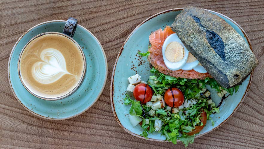 An open-faced smoked trout sandwich served alongside a latte at Geysir Glima Restaurant on the Golden Circle.