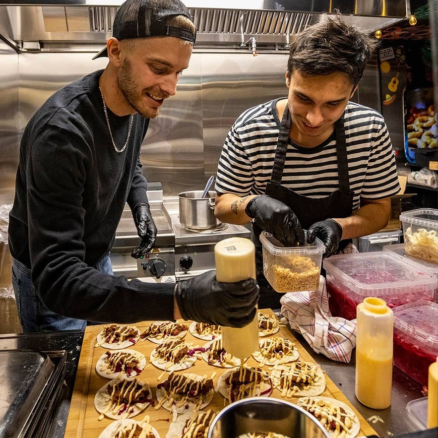 Chefs preparing fusion tacos at the Taco Vagninn stall inside Grodurhusid Food Hall in Hveragerdi Iceland.
