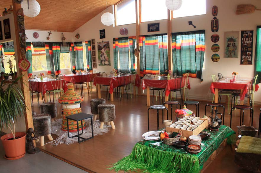 The colorful dining room of Minilik Ethiopian Restaurant in Fludir, Iceland, decorated with traditional Ethiopian art and textiles.