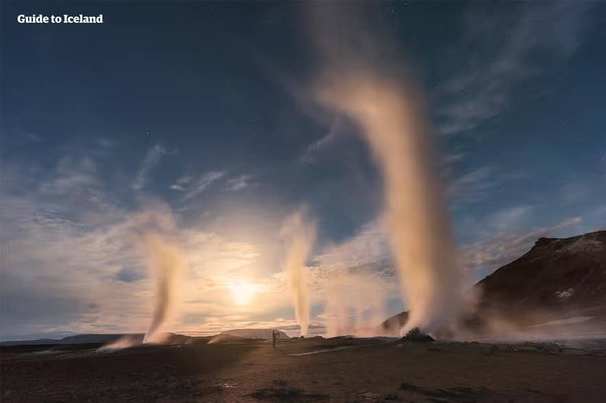 Steam rising from geothermal vents at Hverir in North Iceland during sunset, with swirling columns of steam against a dramatic sky.