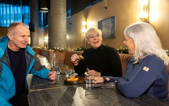 Trois personnes qui rient et dégustent des spécialités lors d'une visite gastronomique à Reykjavik.