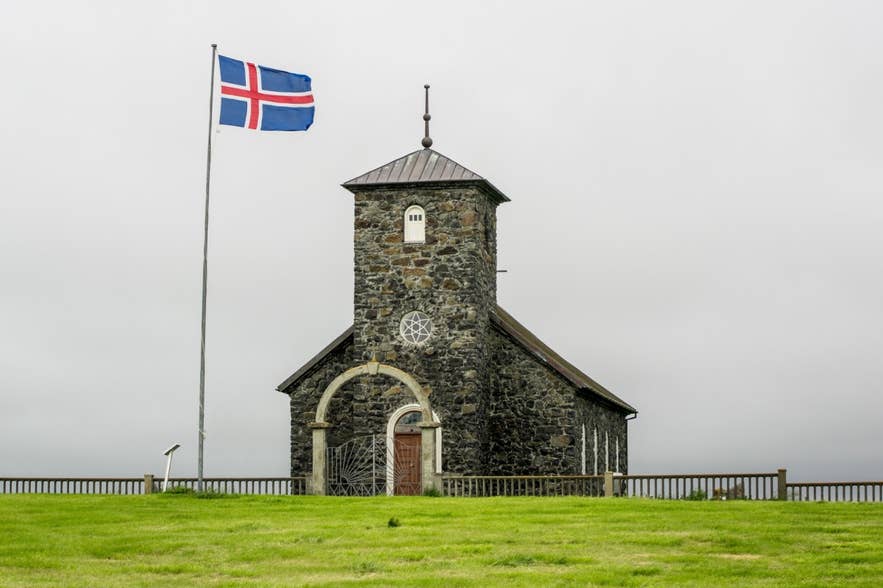 Thingeyrakirkja Church with the Icelandic flag next to it.